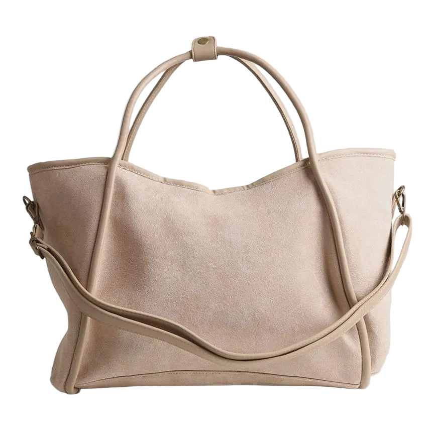 A light beige suede hobo-style tote bag with dual top handles and a detachable shoulder strap, shown on a neutral light gray background.