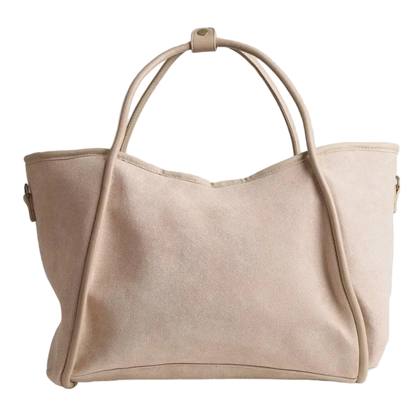 A light beige suede tote bag with dual top handles and a zip-around closure, photographed against a neutral light gray background.