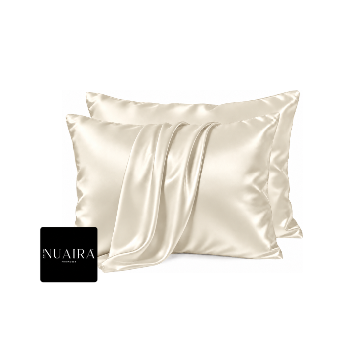Two cream-colored satin pillowcases with a matching draped satin sheet, by 'NUAIRA'.