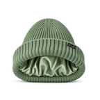 Green ribbed knit beanie hat with a shiny green satin inner lining, shown on a white background with a green NUAIRA brand tag in the lower left corner.