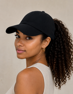 Women wearing a satin-lined backless baseball cap with curly hair in a ponytail.